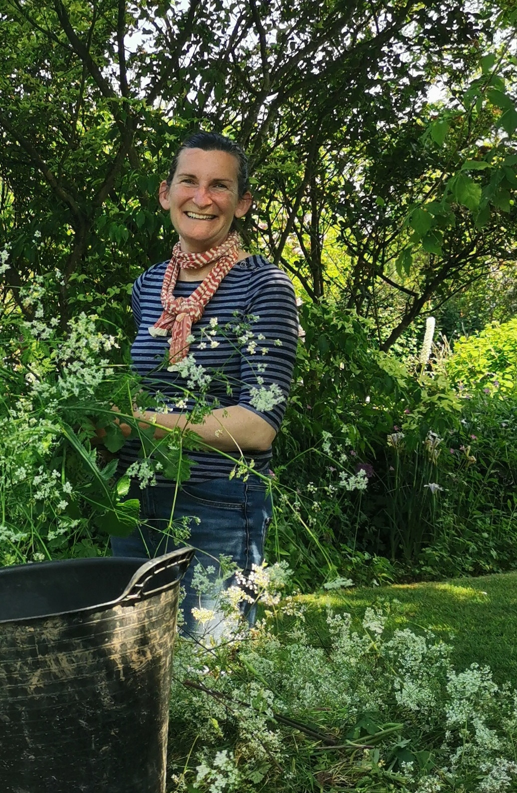 A lady standing smiling amongst flowers