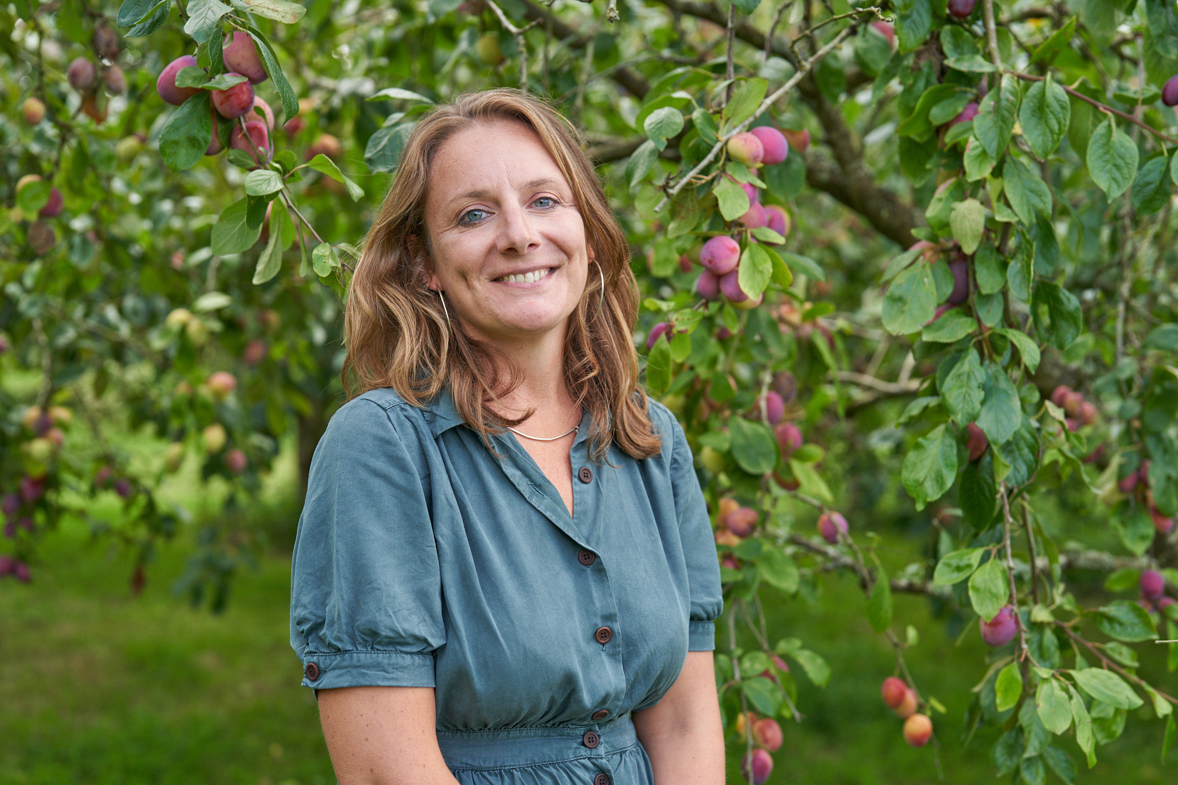 A lady smiling standing amongst trees