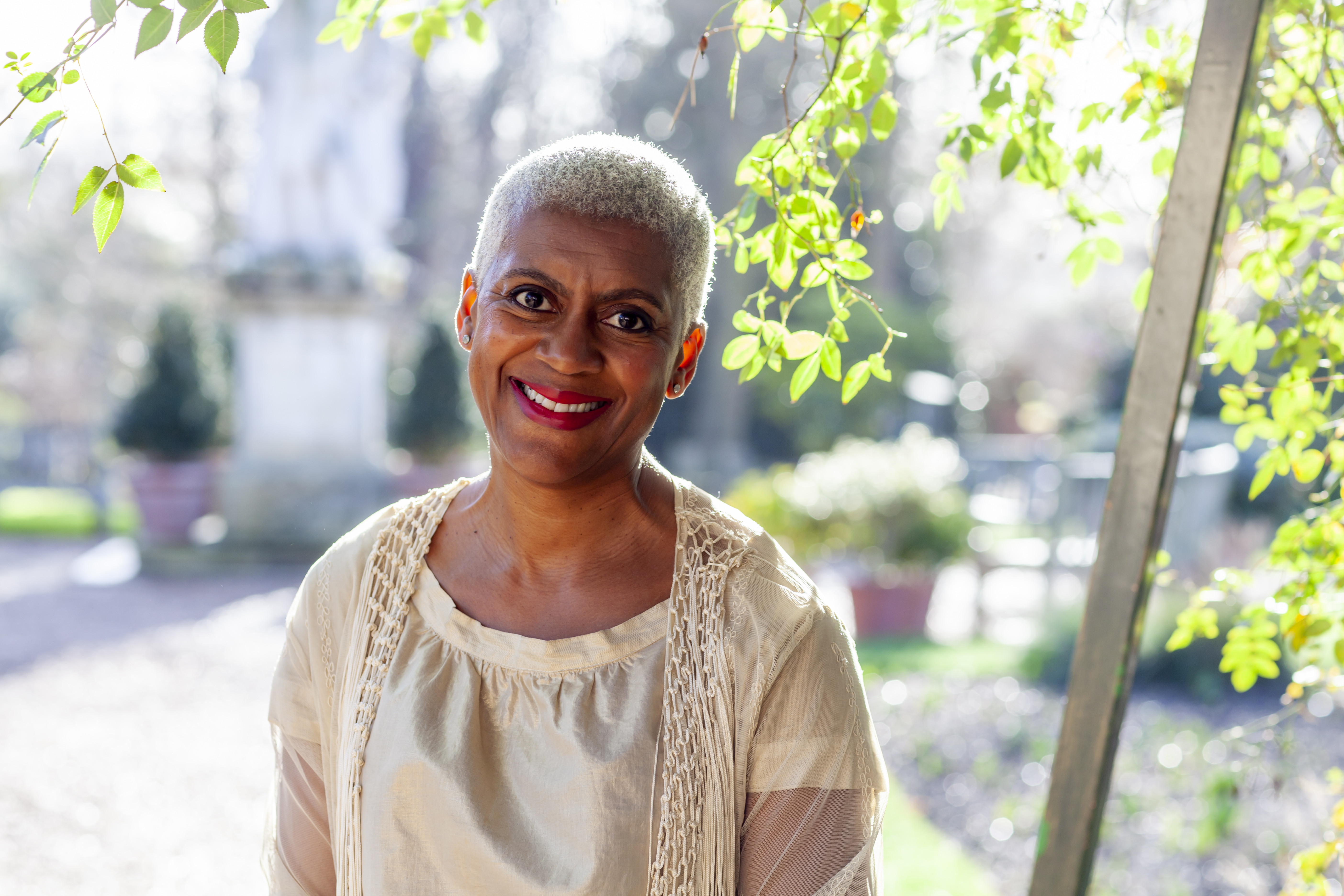 A lady smiling outside in a garden