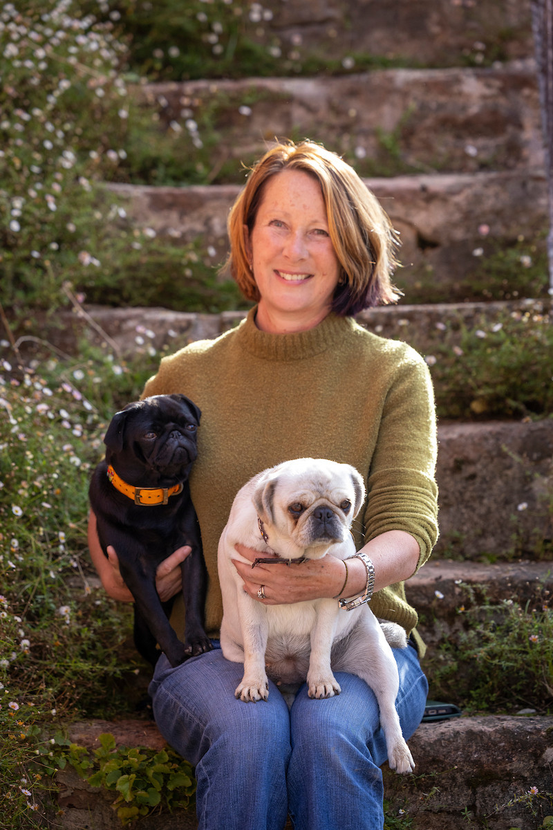 A lady sitting on steps holding two dogs