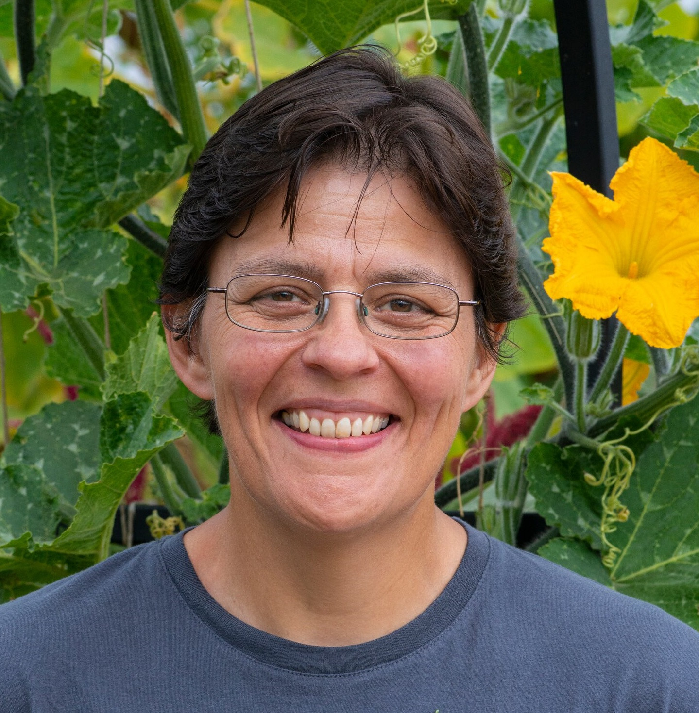 A lady smiling in front of flowers